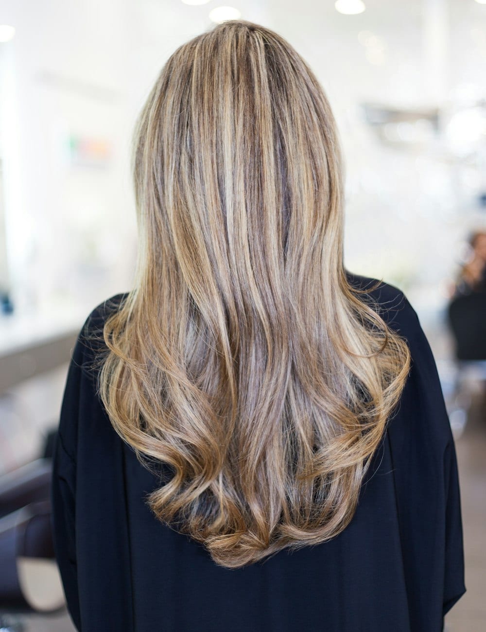 Symbolbild: Lange, in warmen Tönen colorierte Haare in einem hellen Salon.